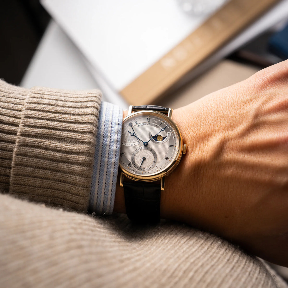 Mann trägt die Breguet Classique 7137BA mit einem Gelbgoldgehäuse in klassischer Form mit einem silbernen Zifferblatt mit jeweils einem anderen handgefertigten Guilloche-Muster für jede Komplikation  an seinem Handgelenk