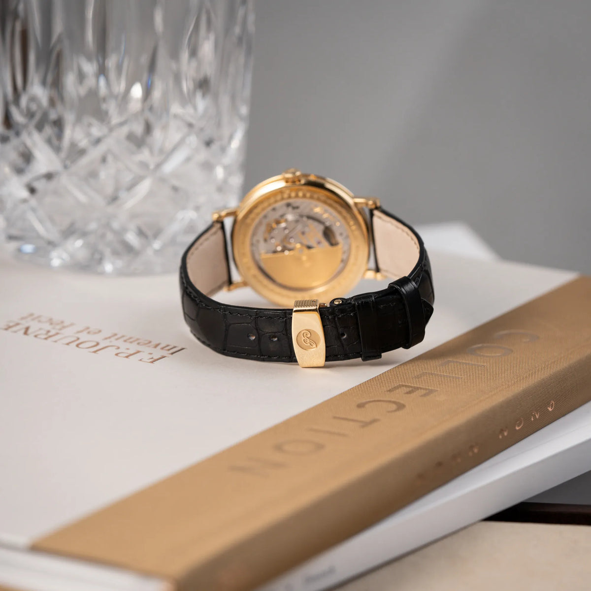 Produktfotografie der Breguet Classique 7137BA mit einem Gelbgoldgehäuse in klassischer Form mit einem silbernen Zifferblatt mit jeweils einem anderen handgefertigten Guilloche-Muster für jede Komplikation  mit Fokus auf dem Lederband und der Gelbgold-Schliesse