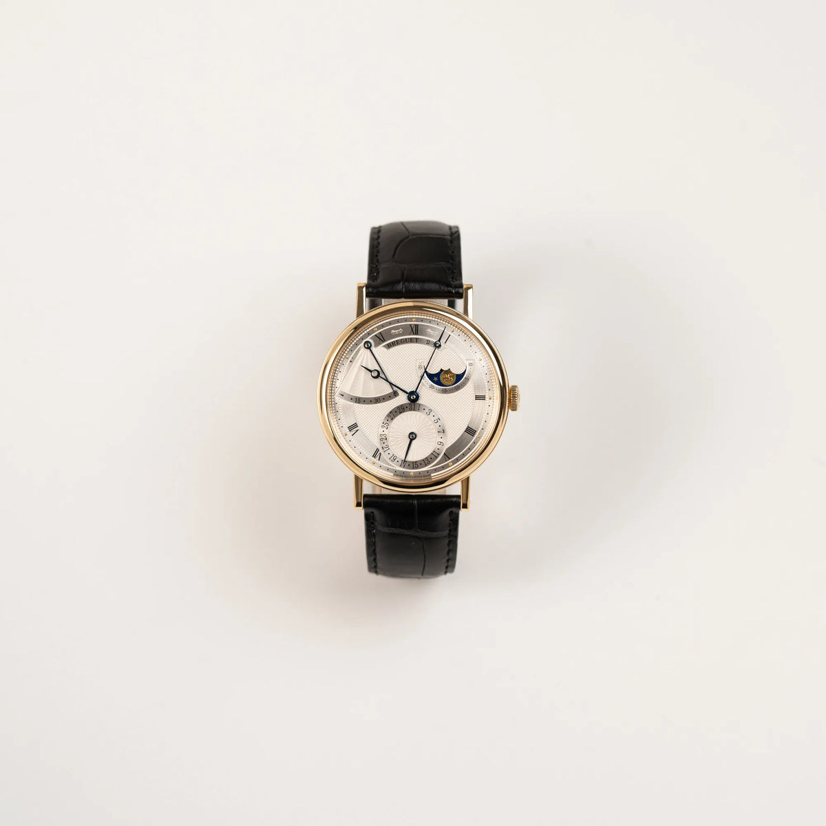 Frontale Ansicht der Breguet Classique 7137BA mit einem Gelbgoldgehäuse in klassischer Form mit einem silbernen Zifferblatt mit jeweils einem anderen handgefertigten Guilloche-Muster für jede Komplikation 