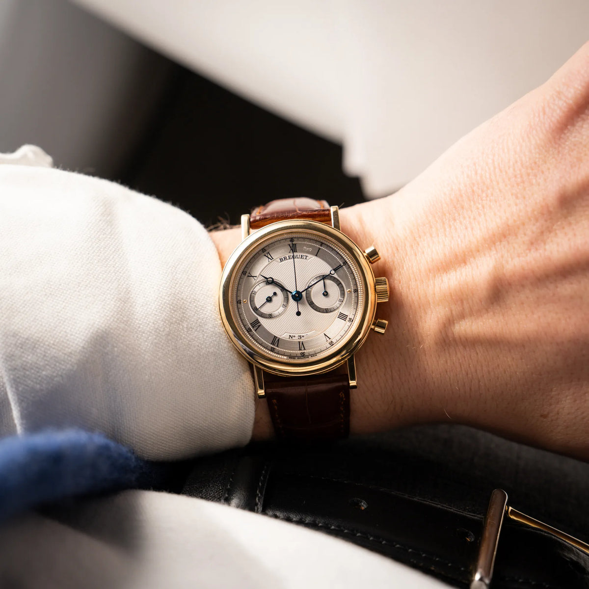 Wristshot mit dem Breguet Classique Chronograph der Referenz 5237 in Gelbgold mit silbernem guillochiertem Zifferblatt am braunem Lederband 