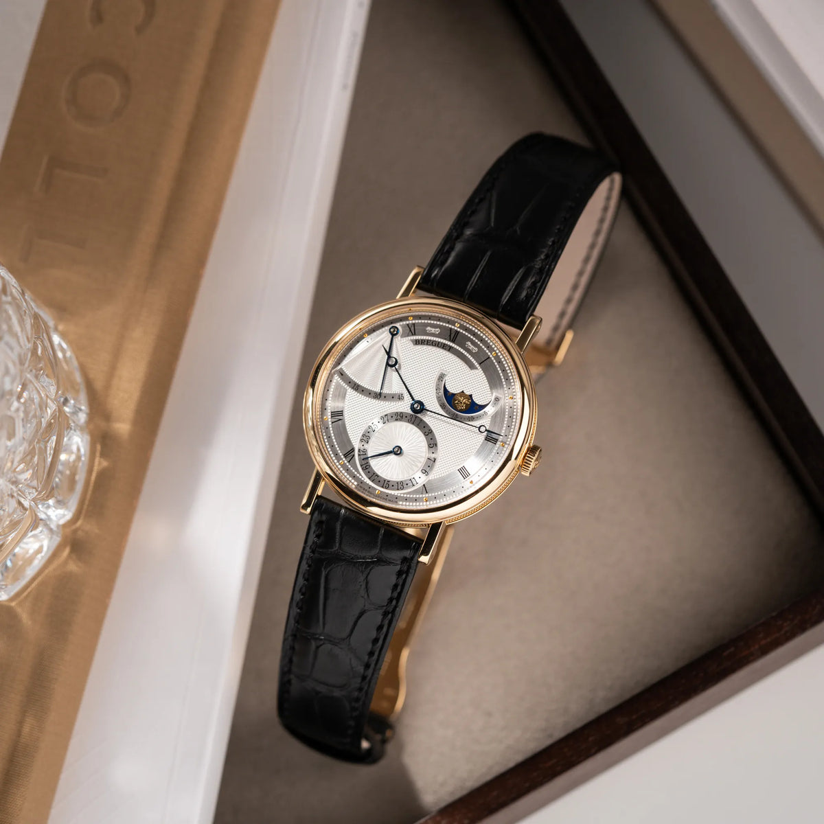 Produktfotografie von der  Breguet Classique Mondphase 7137 in Gelbgold mit silbernen, verschieden guillochiertem Zifferblatt auf Juwelierstablet