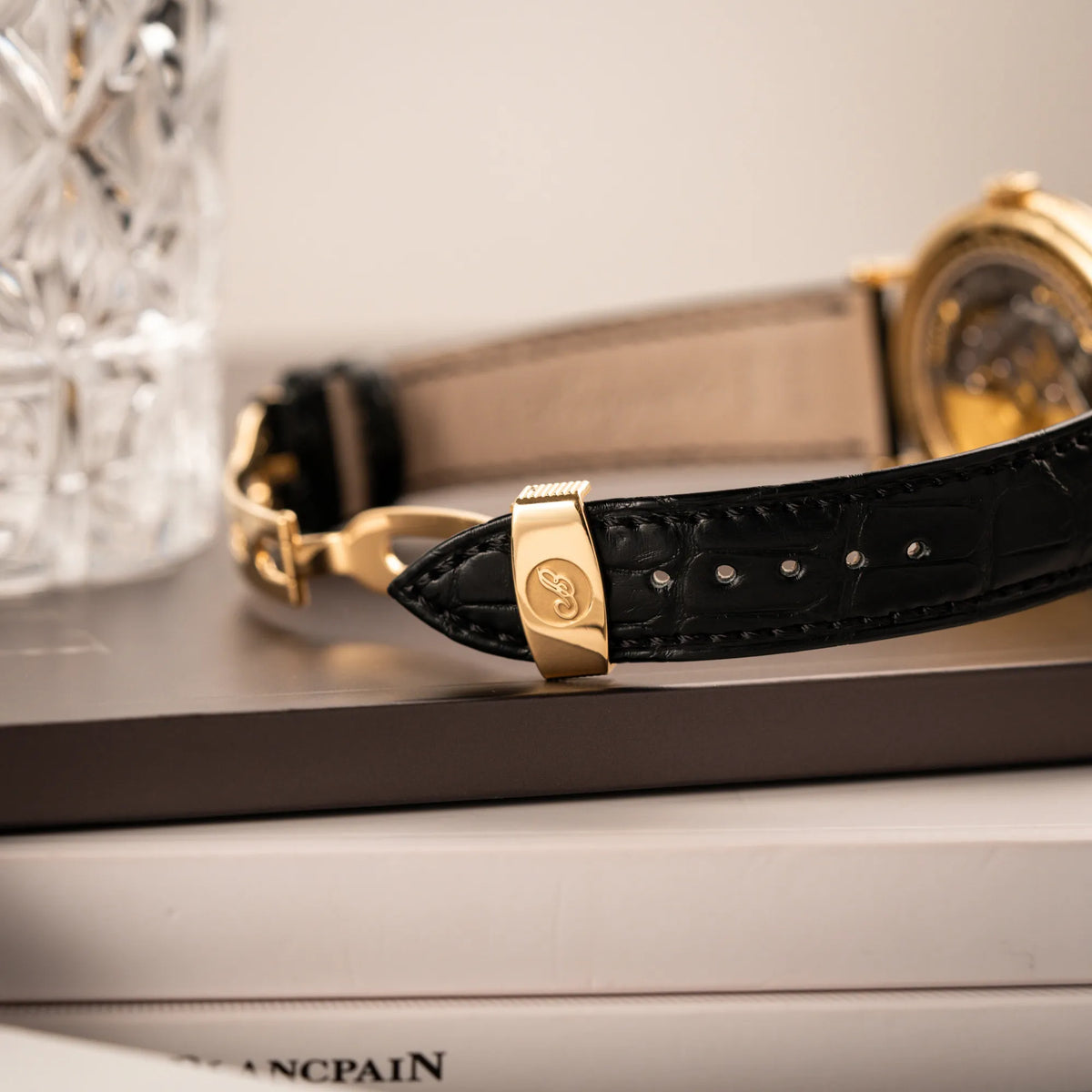 Detailaufnahme der originalen Breguet-Faltschliesse aus 750er Gelbgold an dem schwarzen Lederband der  Breguet Classique Mondphase 7137 in Gelbgold mit silbernen, verschieden guillochiertem Zifferblatt