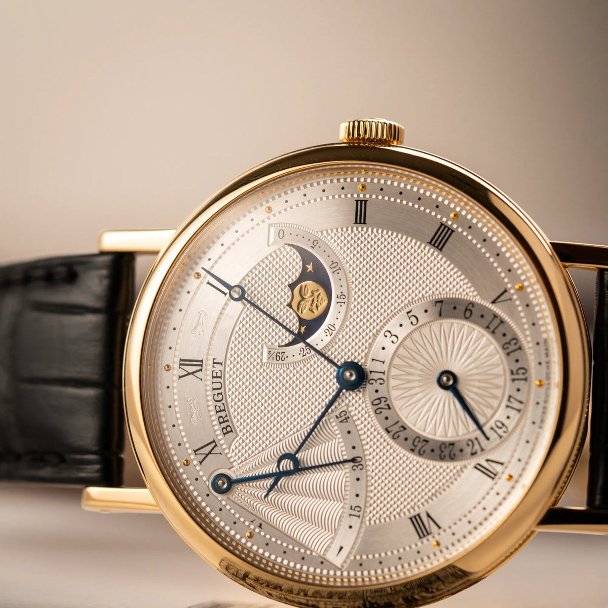 Detailaufnahme der seitlich liegenden  Breguet Classique Mondphase 7137 in Gelbgold mit silbernen, verschieden guillochiertem Zifferblatt