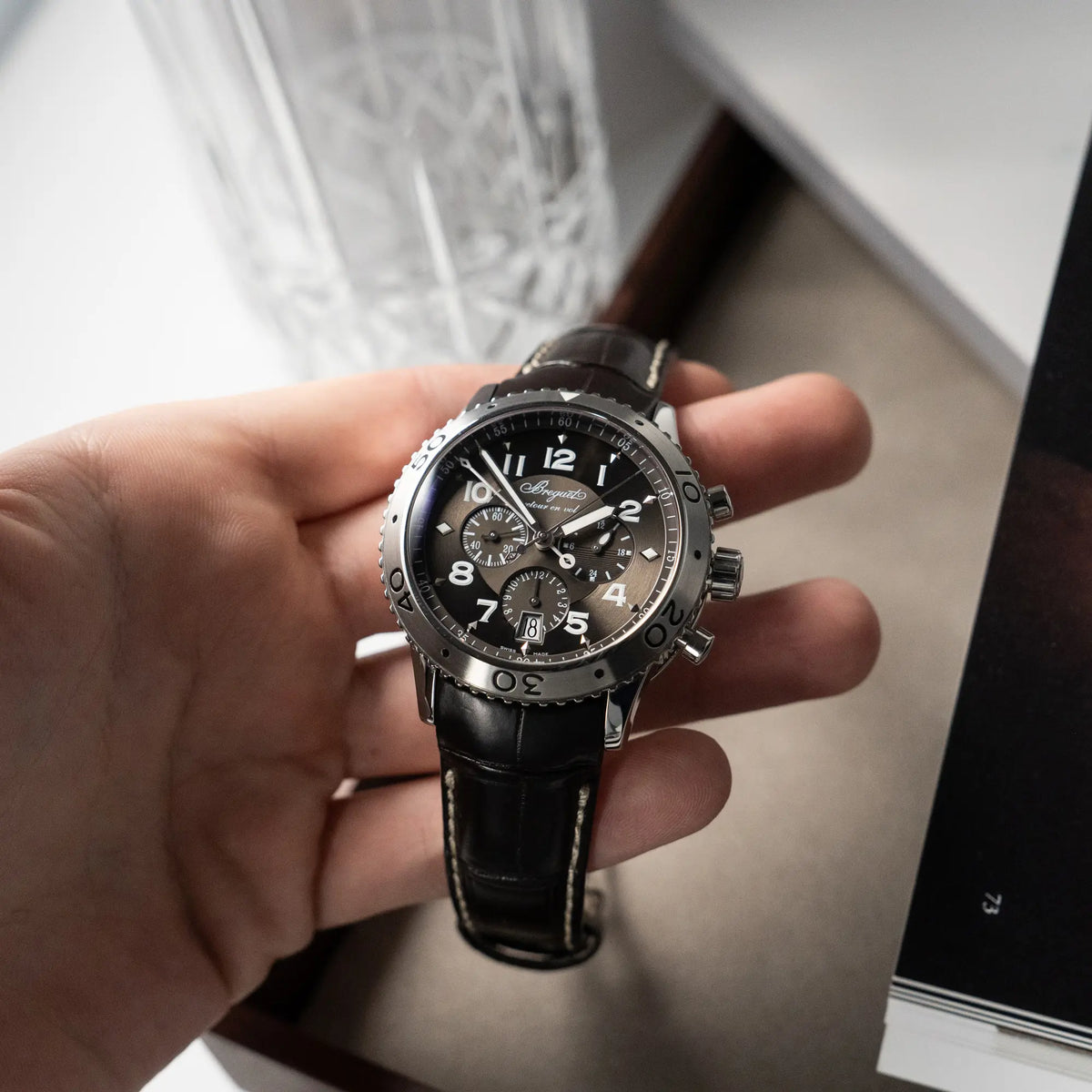 Mann hält den Breguet Type XX Flyback Chronographen 3810ST mit braunem Zifferblatt in seiner Hand und präsentiert die Uhr in die Kamera