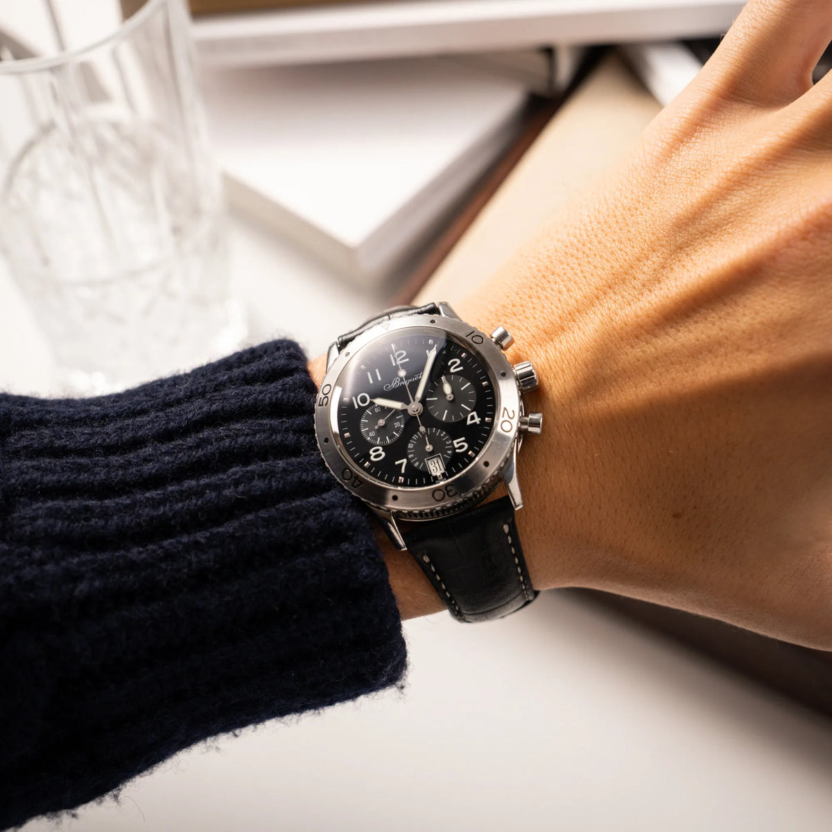 Mann trägt die Breguet Type XX Aéronavale Transatlantique der Referenz 3820ST mit schwarzem Lack-Zifferblatt am originalen schwarzen Breguet-Lederband an seinem Arm