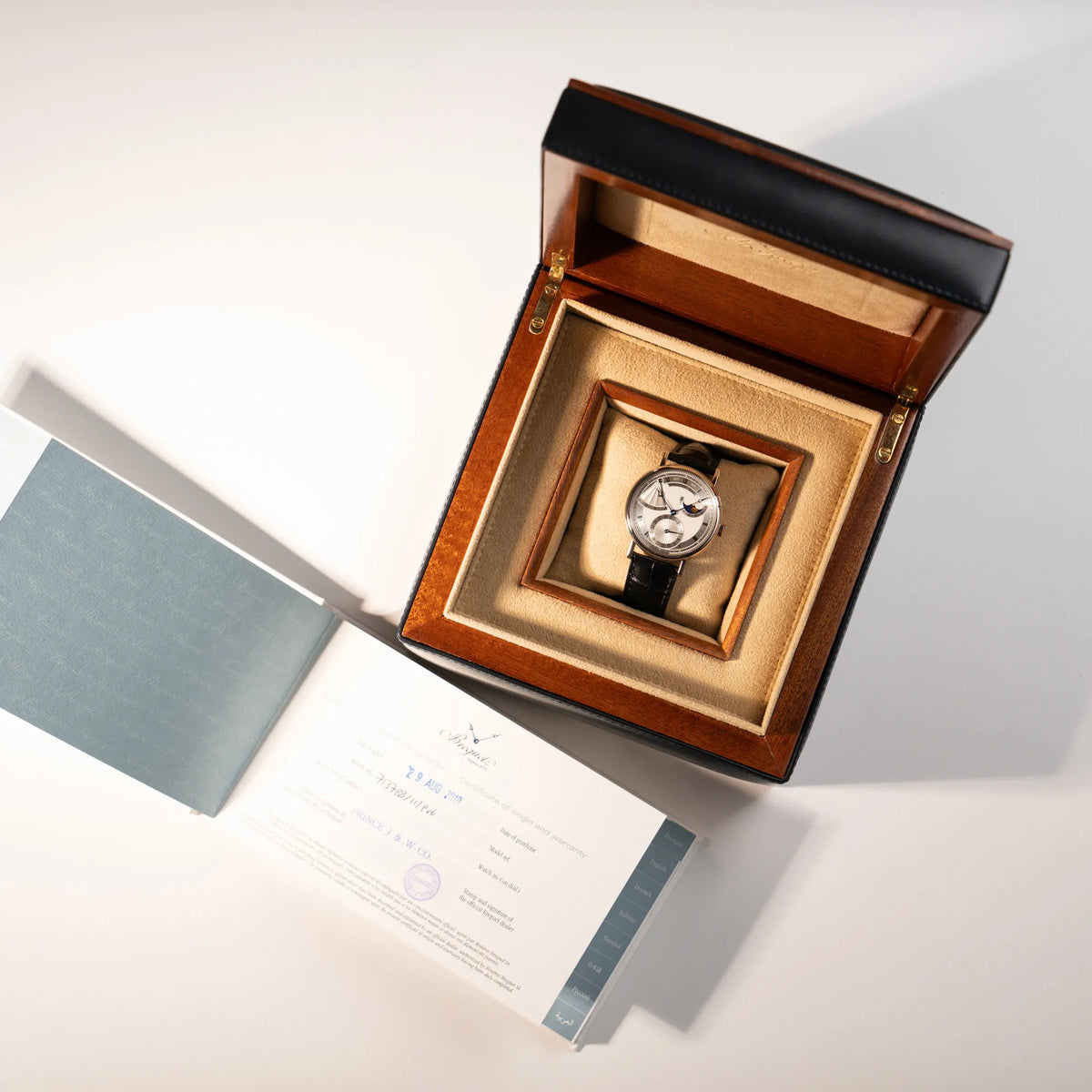 Lieferumfang zugehörig zu der Breguet Classique Moonphase der Referenz 7137 in Weissgold mit 3-fach guillochiertem Zifferblatt und Mondphase-Anzeige, bestehend aus Uhr, Box und Garantiekarte