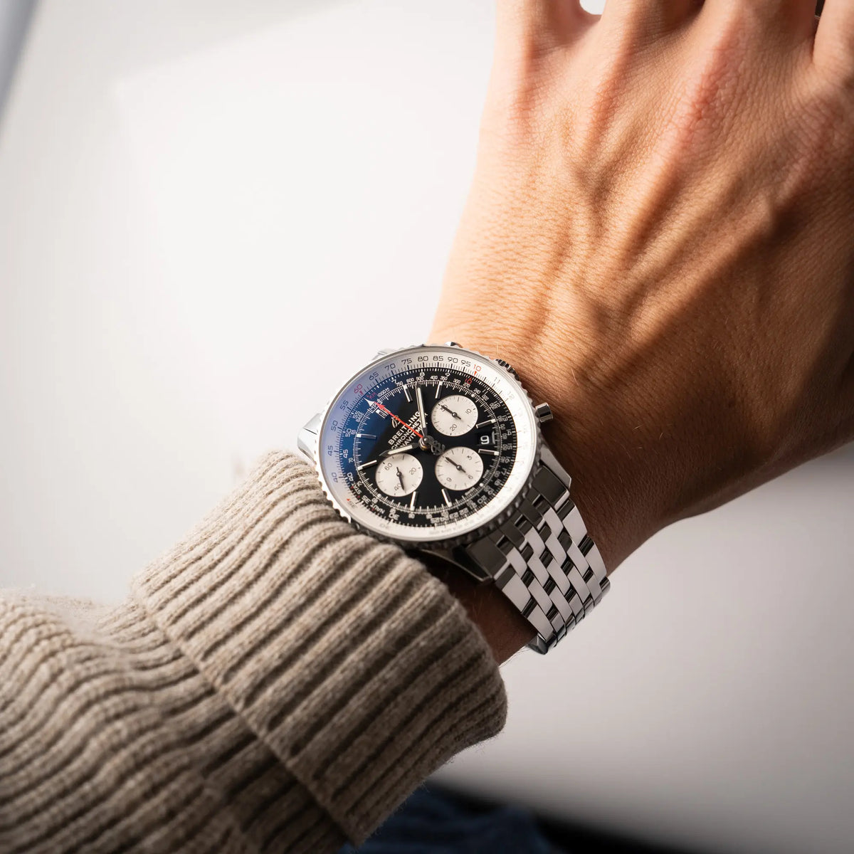Mann trägt die Wristshot mit der Breitling Navitimer B01 Chronograph der Referenz AB0121211B1A1 mit Reverse-Panda Zifferblatt in schwarz mit weißen Hilfszifferblätter an seinem Handgelenk