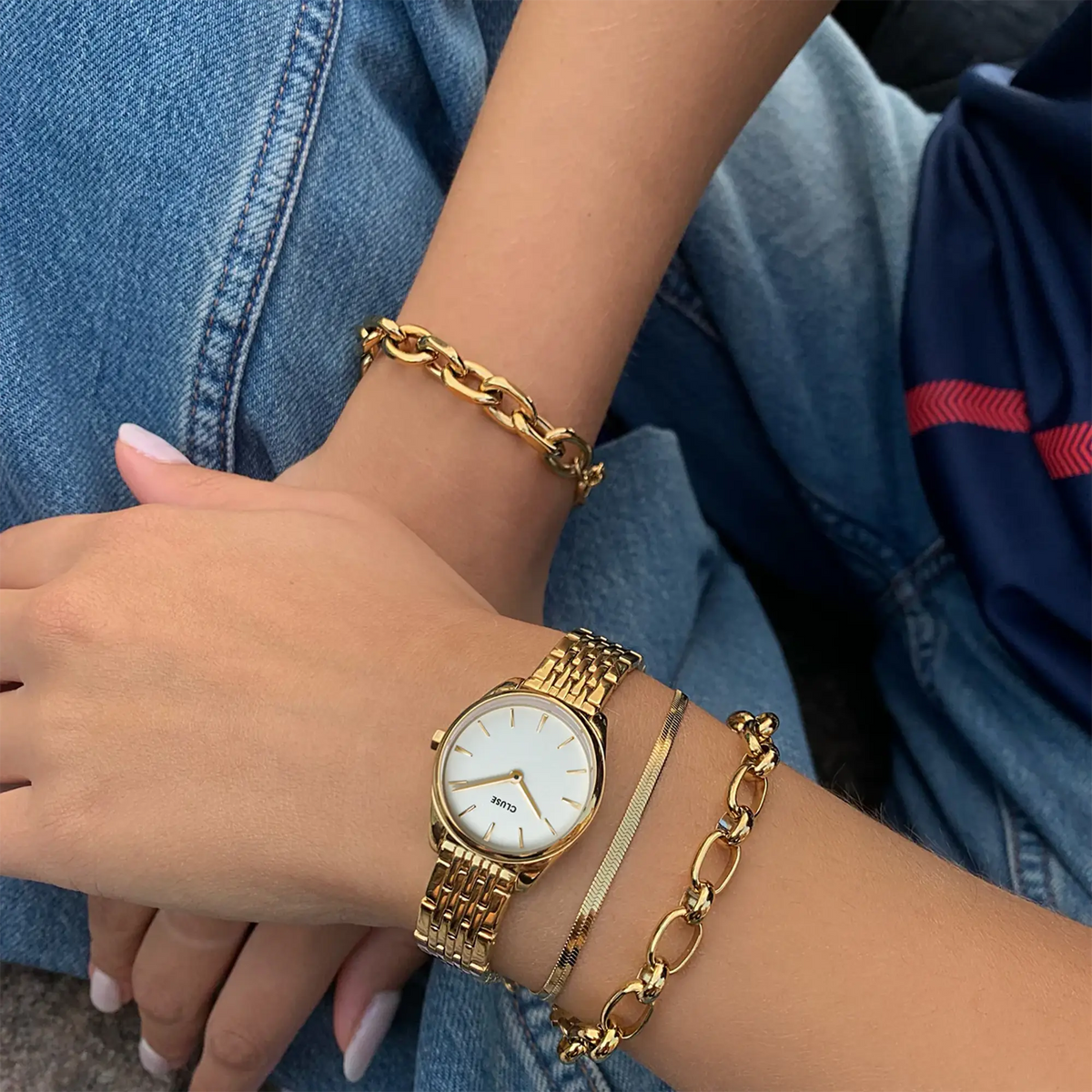 Lifestyle-Bild mit der goldfarbenen Cluse Damenuhr Feroce Mini CW11705 mit rundem Gehäude, einem weißem Zifferblatt und einem feingliedrigem, goldfarbenem Uhrenarmband