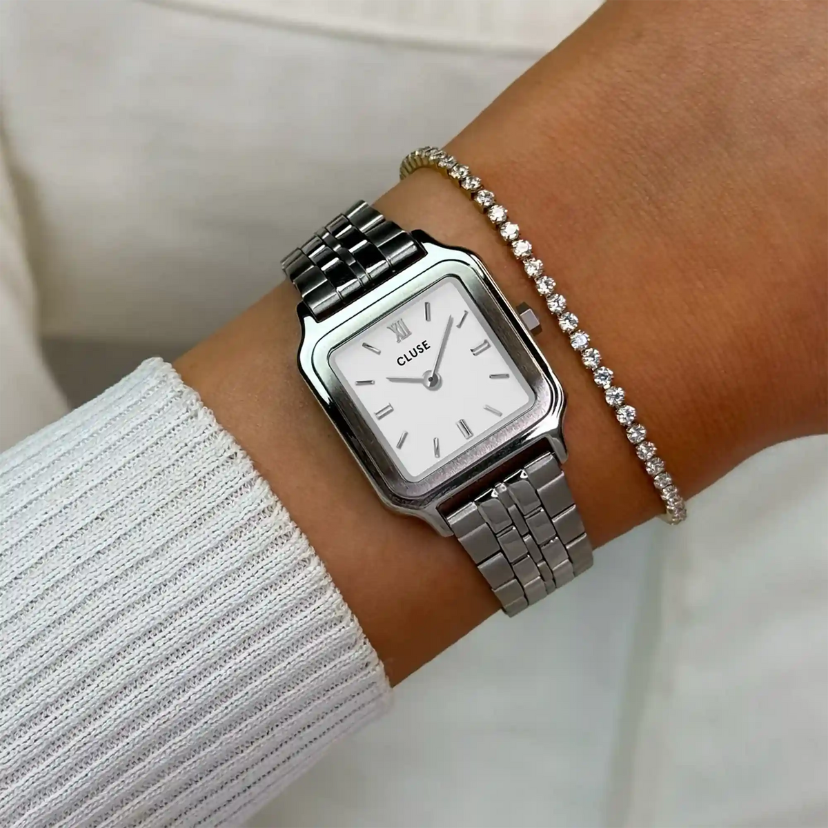 Wristshot mit der silberfarbenen Cluse Damenuhr Gracieuse Petite CW11817 mit weißem Zifferblatt in quadratischem Uhrengehäuse an einem silberfarbenem Edelstahl-Armband