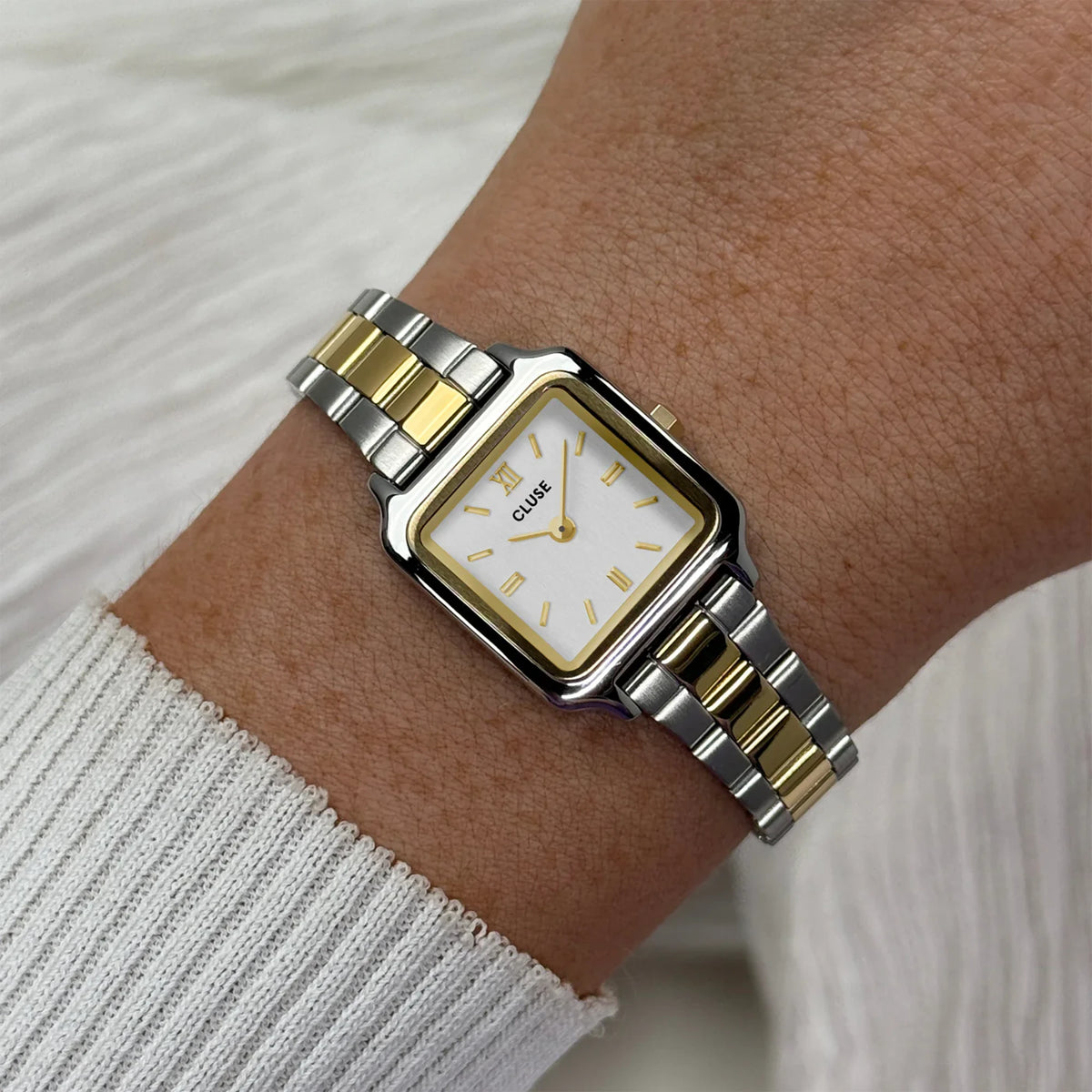 Wristshot mit der stahl-goldfarbenen Cluse Damenuhr Gracieuse Mini CW15501 mit quadratischen Gehäuse, einem weißem Zifferblatt und einem passenden stahl-goldfarbenen Uhrenarmband 