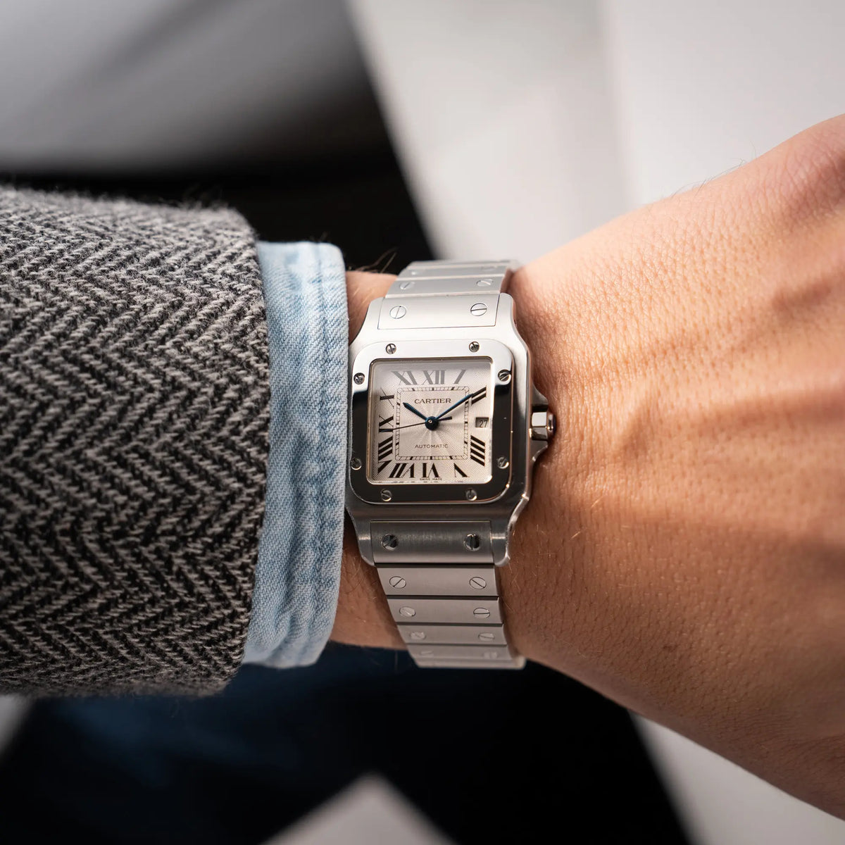 Mann trägt die Cartier Santos Galbée 2913 in Edelstahl mit weiß-silbernem Zifferblatt am Stahlband mit der klassischen Cartier-Schrauben-Optik an seinem Handgelenk