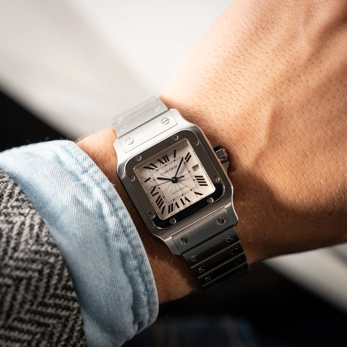 Wristshot mit der Cartier Santos Galbée 2913 in Edelstahl mit weiß-silbernem Zifferblatt am Stahlband mit der klassischen Cartier-Schrauben-Optik an einem Männerhandgelenk