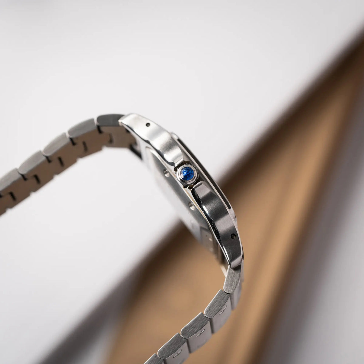 Seitliche Gehäuseflanke mit Blicka uf die Aufzugskrone der Cartier Santos Galbée 2913 in Edelstahl mit weiß-silbernem Zifferblatt am Stahlband mit der klassischen Cartier-Schrauben-Optik