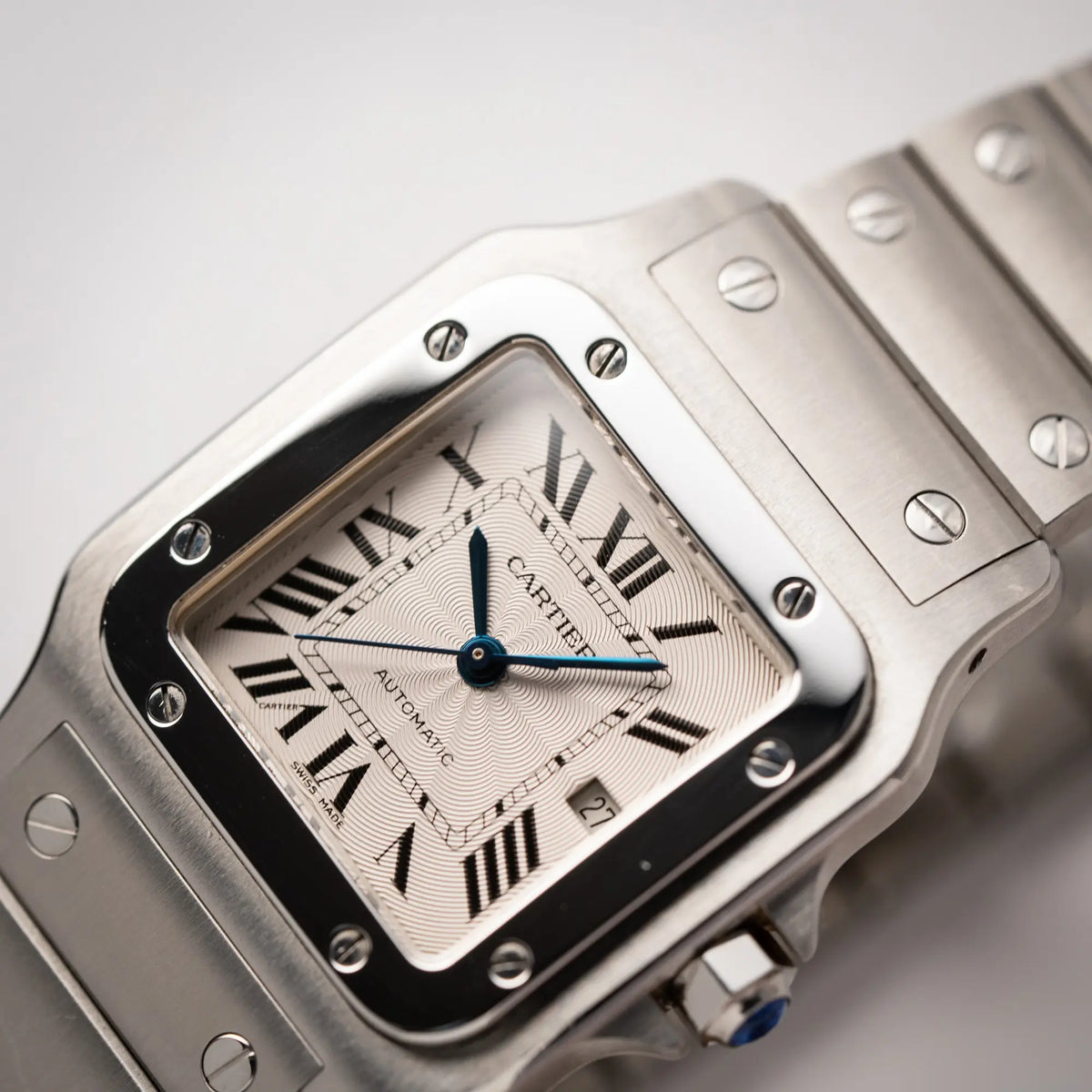 Detailaufnahme der Cartier Santos Galbée 2913 in Edelstahl mit weiß-silbernem Zifferblatt am Stahlband mit der klassischen Cartier-Schrauben-Optik zeigt die Guillochierung des Zifferblatts