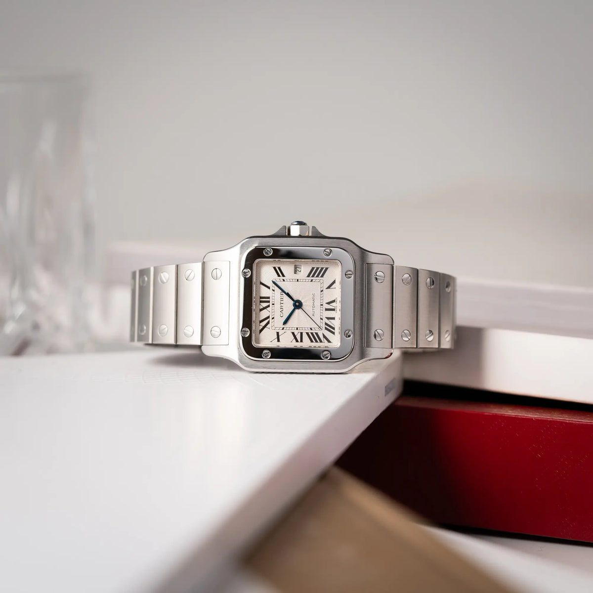 Cartier Santos Galbée 2913 in Edelstahl mit weiß-silbernem Zifferblatt am Stahlband mit der klassischen Cartier-Schrauben-Optik liegt seitlich auf der gehäuseflanke