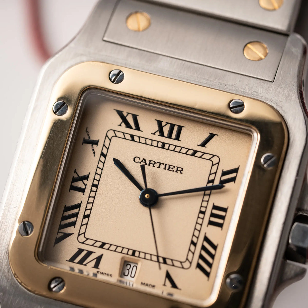 Detailaufnahme der Cartier Santos Galbee BiColor der Referenz 187901 mit Stahl-Gold-Gehäuse am Stahlband  mit dem Cartier-typischen Schrauben, die ebenfalls in Gelbgold gehalten sind, und einem cremfarbenen Zifferblatt mit klassischen römischen Indizes