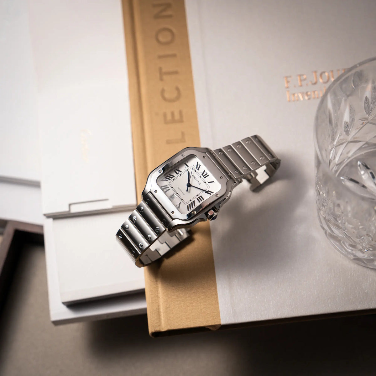 Künstlerische Produktfotografie der Cartier Santos de Cartier als großes Modell der Referenz WSA0018 mit dem klassischen weißen Zifferblatt und römischen Indizes, während die Uhr auf dem Band aufgestellt wurde