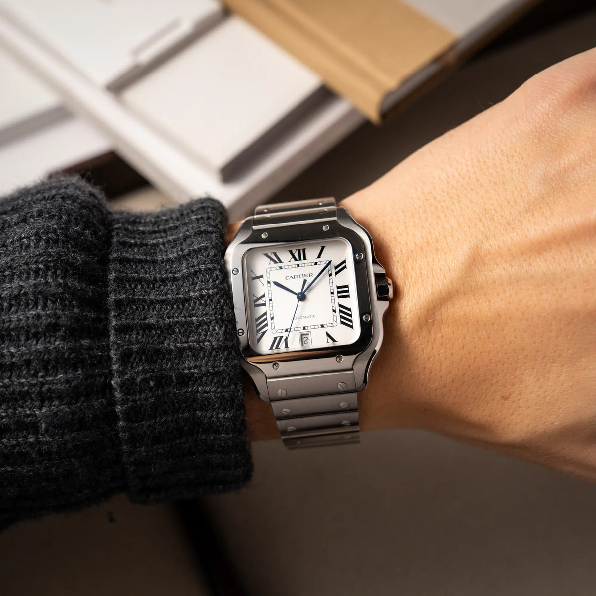 Wristshot mit der Cartier Santos de Cartier als großes Modell der Referenz WSA0018 mit dem klassischen weißen Zifferblatt und römischen Indizes zeigt die Uhr mit den polierten und satinierten Oberflächen