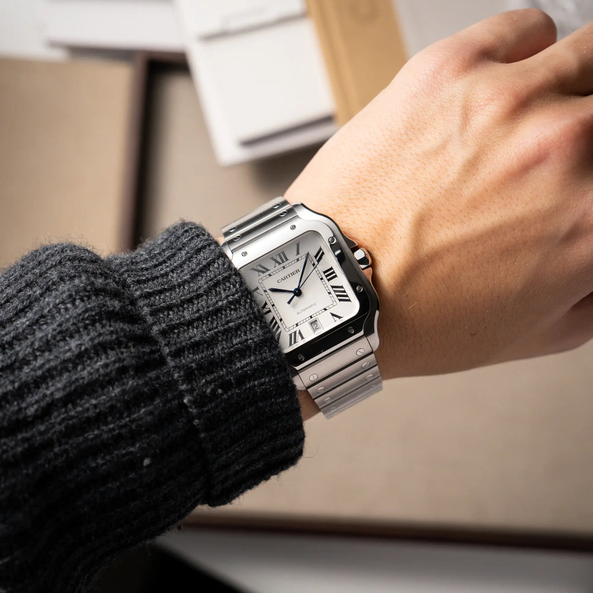 Mann trägt die Cartier Santos de Cartier als großes Modell der Referenz WSA0018 mit dem klassischen weißen Zifferblatt und römischen Indizes an seinem Handgelenk