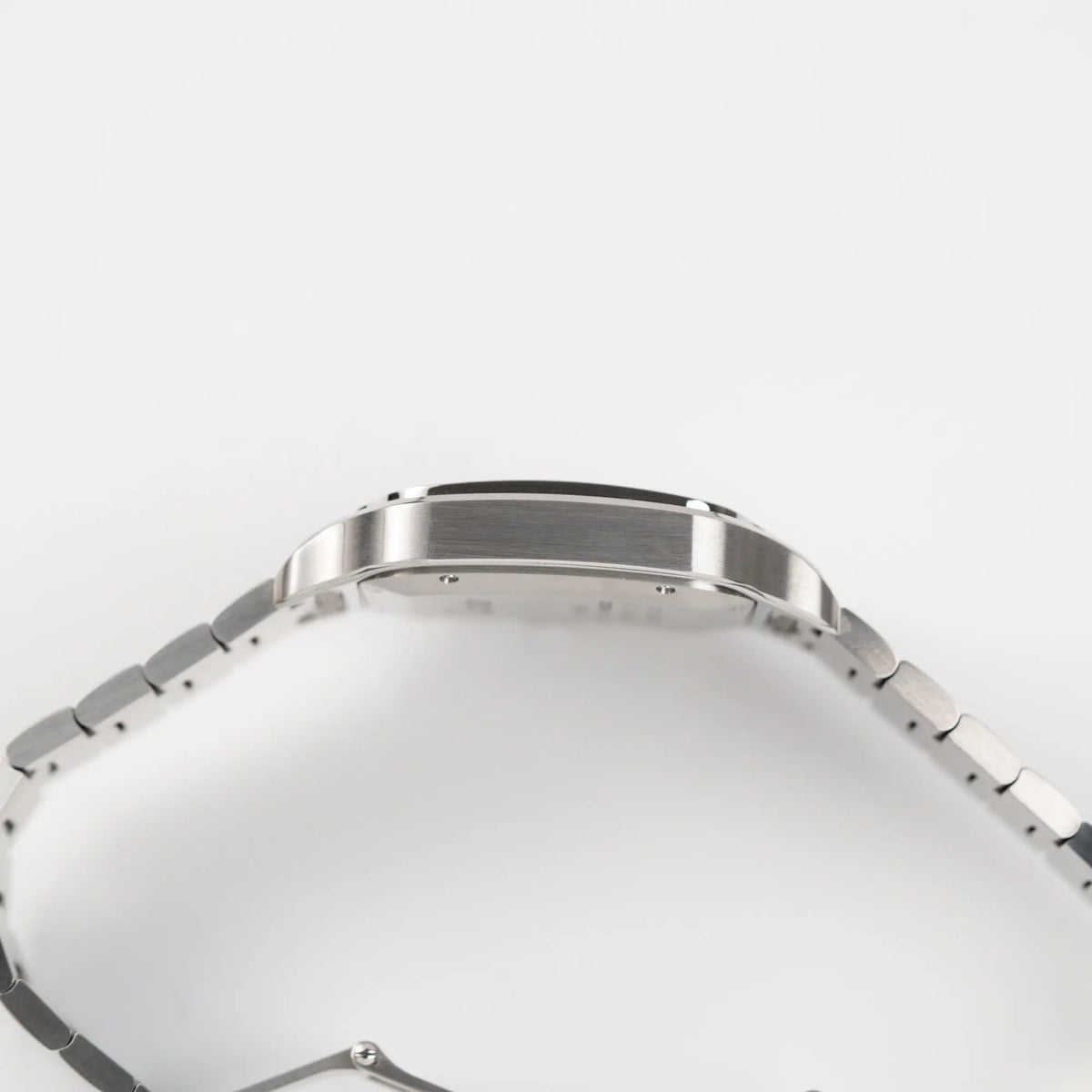 Seitliche satinierte Gehäuseflanke der Cartier Santos de Cartier als großes Modell der Referenz WSA0018 mit dem klassischen weißen Zifferblatt und römischen Indizes 