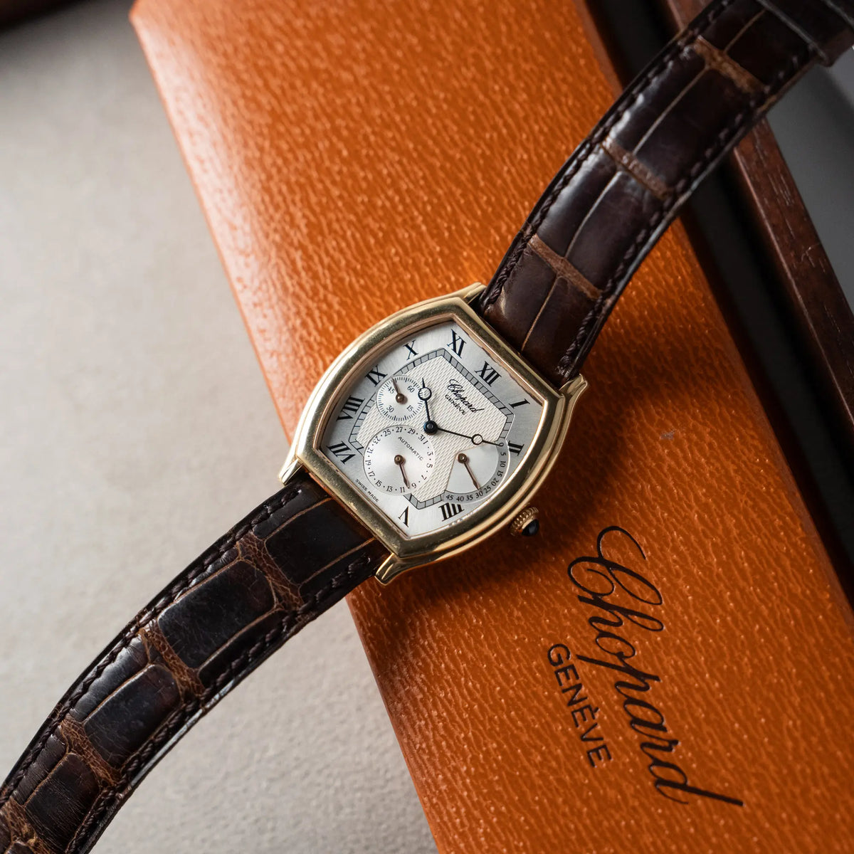 Produktfotografie der Chopard Tonneau Powerreserve 2248 mit Gehäuse aus 18k Roségold zusammen mit der originalen Uhrenbox