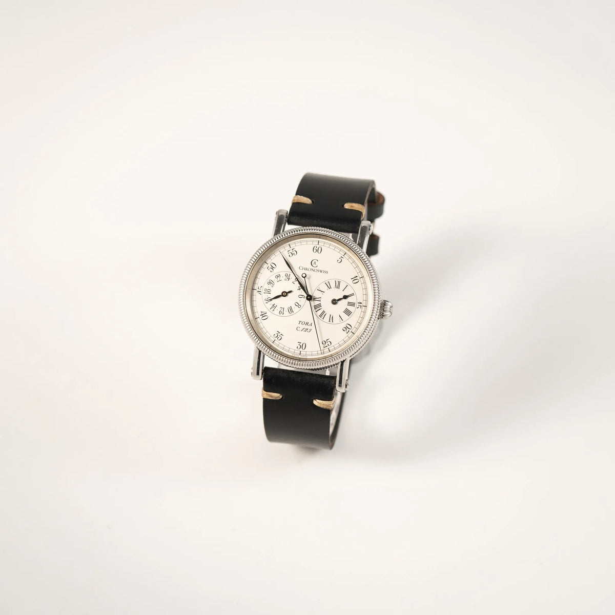 Leicht schräge Ansicht der Chronoswiss Regulator Tora C123 mit weißem Zifferblatt mit zwei symmetrisch angeordneten Hilfszifferblättern mit römischen Indizes