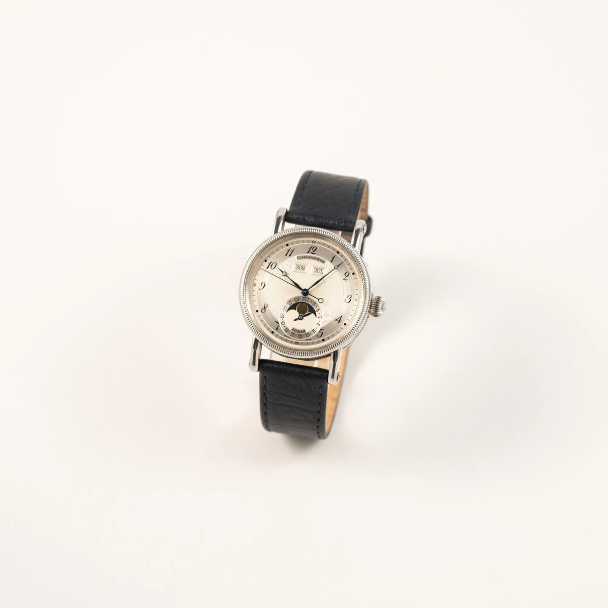 Leicht schräge Ansicht der Chronoswiss Klassic Luna Mondphase CH9323 mit silbernem, guillochiertem Zifferblatt mit Kalenderanzeige auf 12 Uhr und einer Mondphase-Anzeige bei 6 Uhr