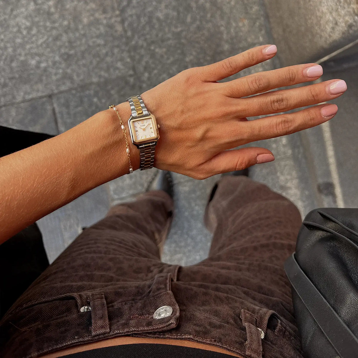 Lifestylebild mit der stahl-goldfarbenen Cluse Damenuhr Gracieuse Mini CW15501 mit quadratischen Gehäuse, einem weißem Zifferblatt und einem passenden stahl-goldfarbenen Uhrenarmband 