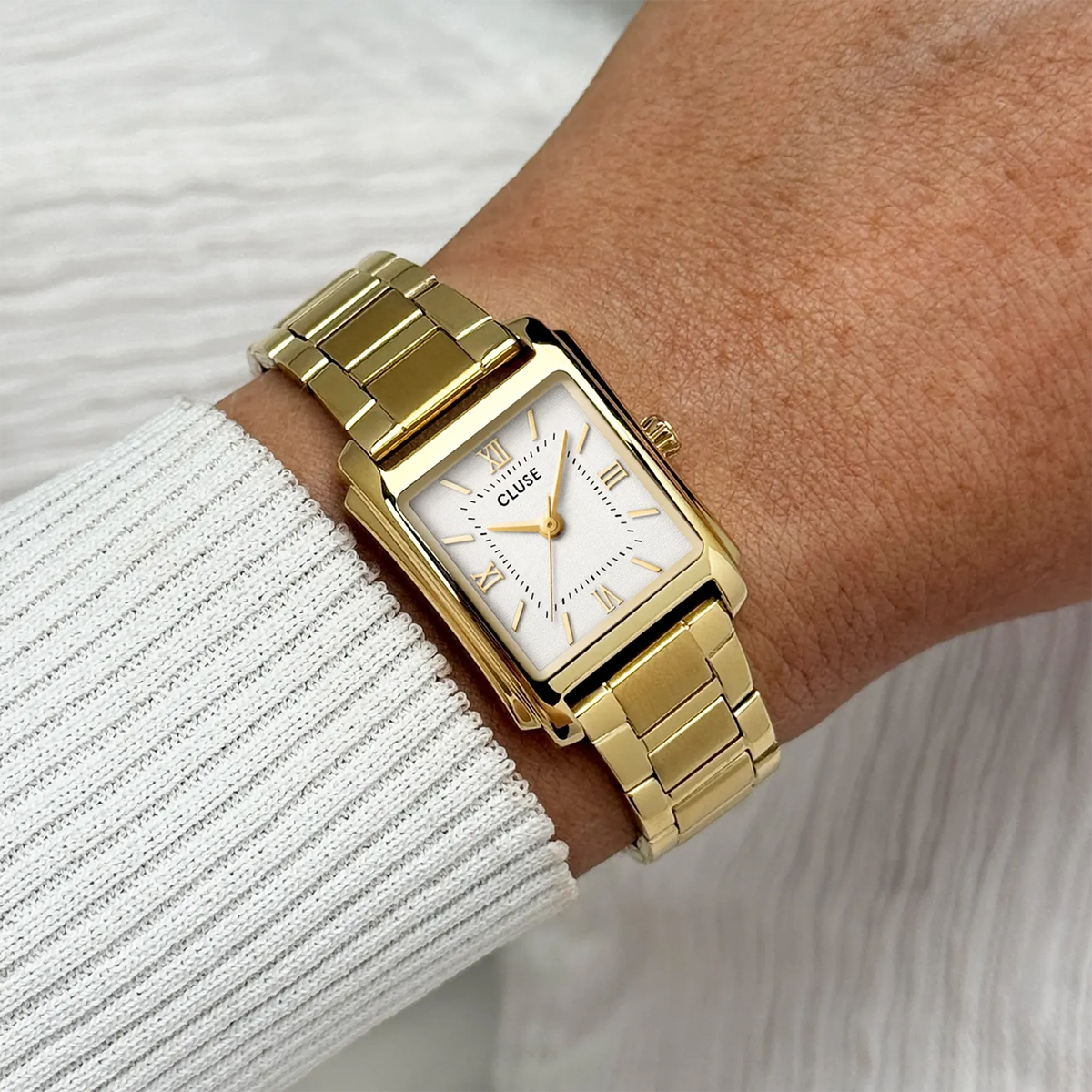 Wristshot mit der rechteckigen, goldfarbenen Cluse Anglée Damenuhr CW16601  mit weißem, fein strukturierten Zifferblatt