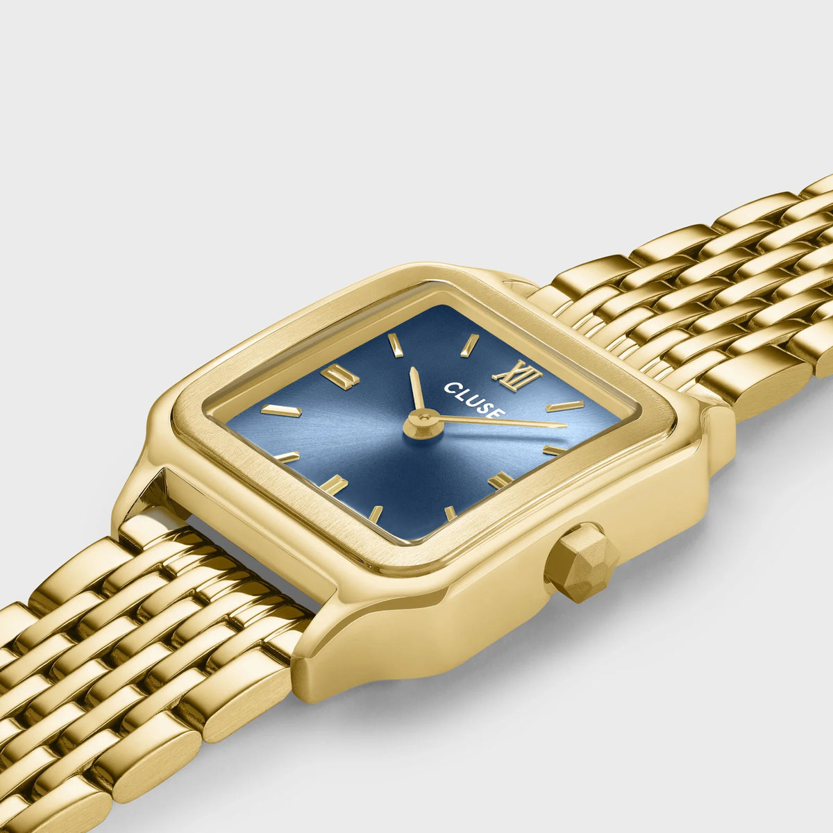 Leicht schräge Ansicht der goldfarbenen Cluse Gracieuse Petite Damenuhr mit rechteckigem Gehäuse und blauem Zifferblatt an einem feingliedrigen Doppel-Armband