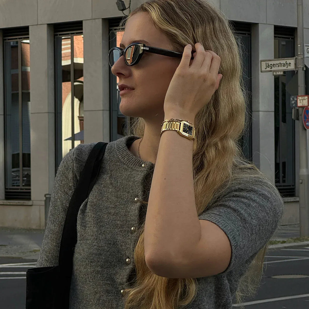 Lifestyleshot einer Frau mit der der goldfarbenen Cluse Gracieuse Damenuhr mit rechteckigem Gehäuse und schwarzen  Zifferblatt am Handgelenk