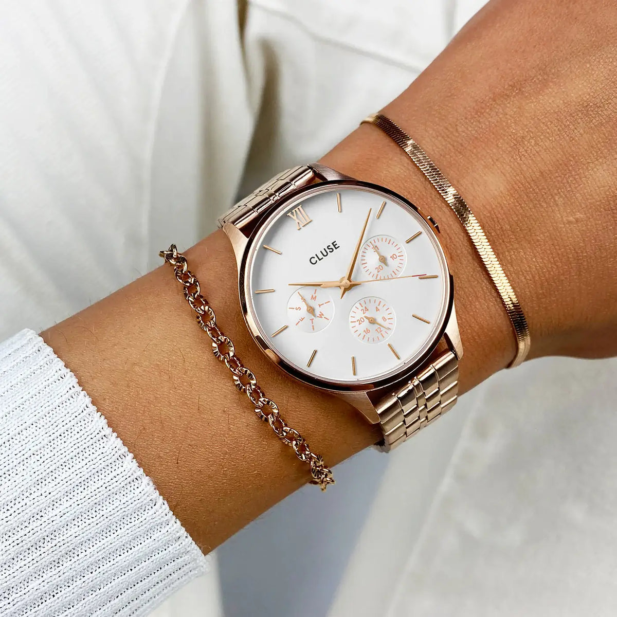 Wristshot mit der Cluse Stahl-Uhr "Minuit Multifunction" im Rosègold-Look mit weißem Zifferblatt und drei Sub-Dials zur Wochentags-, Datums-Anzeige und 24 Stunden-Zähler