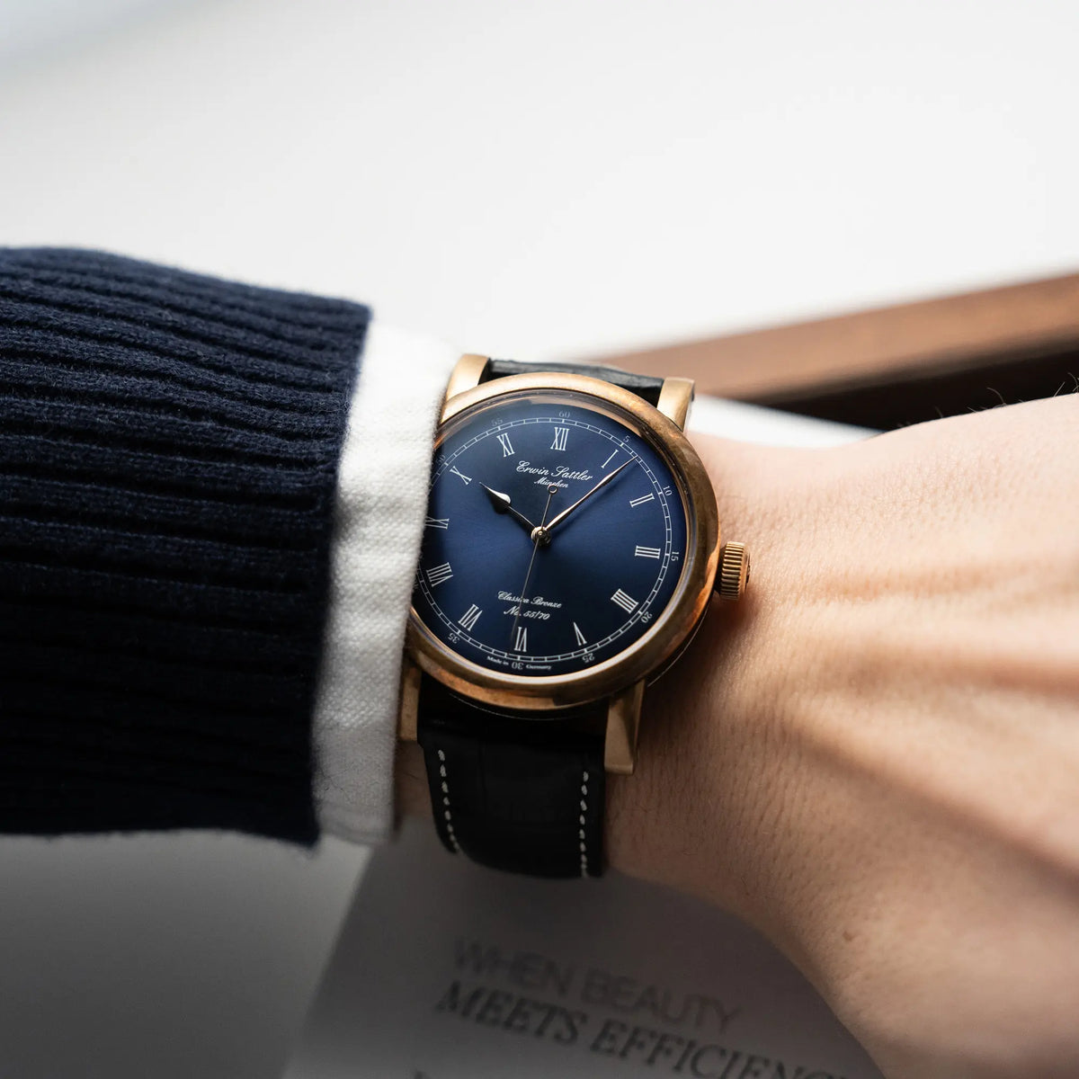 Mann trägt die limitierte Erwin Sattler Classica Armbanduhr in einem Bronze-Gehäuse mit blauem Zifferblatt an seinem Handgelenk für einen Wristshot