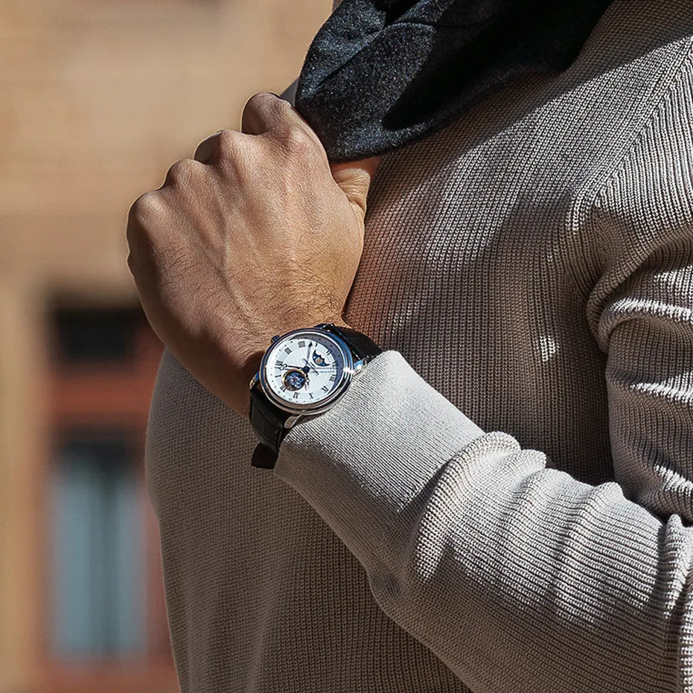Mann in hellbeigen Strickpullover trägt die Heart Beat Moonphase Date Armbanduhr von Frederique Constant aus der Classics Kollektion an seinem Handgelenk