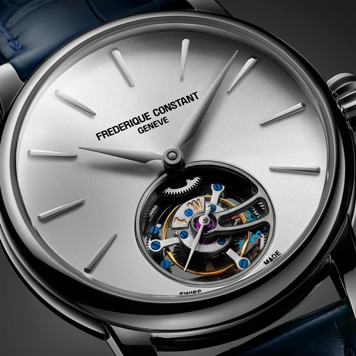 Detailaufnahme des Frederique Constant Manufacture Classic Tourbillon FC-980S3H6 in Stahlgeh mit silberfarbenem Zifferblatt und Tourbillon-Käfig bei 6 Uhr an einem dunkelblauen Alligator-Lederband  mit Blick auf das sonnen-guilloche-Zifferblatt