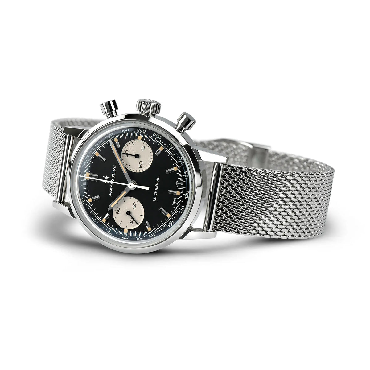 Hamilton American Classic Intra-Matic Auto Chrono H38429130 mit dem Reverse-Panda Zifferblatt an einem feingliedrigen Mesh-Armband liegt seitlich auf dem Uhrengehäuse