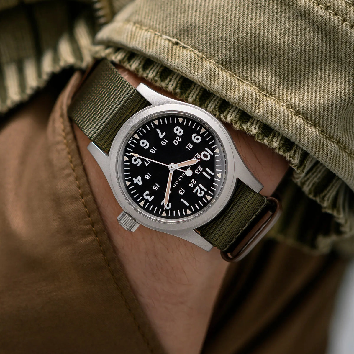 Wristhot mit der Hamilton Khaki Field Mechanical H69439931 mit weißem Zifferblatt an einem olivgrünem Nato-Textil-Armband
