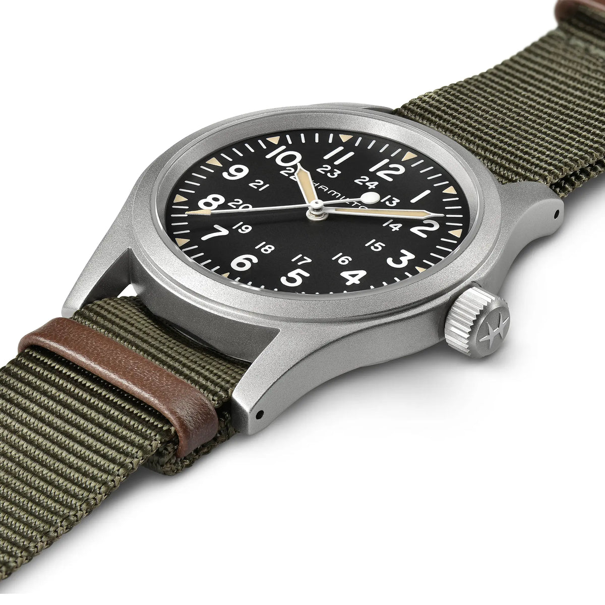 Leicht schräge Ansicht der Hamilton Khaki Field Mechanical H69439931 mit weißem Zifferblatt an einem olivgrünem Nato-Textil-Armband