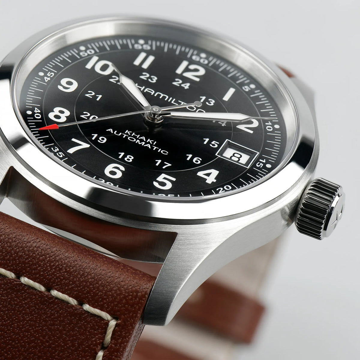 Detailaufnahme mit Fokus auf dem Bandanstoß von der Hamilton Khaki Field Auto H70455533 mit schwarzem Zifferblatt an einem braunen Lederband