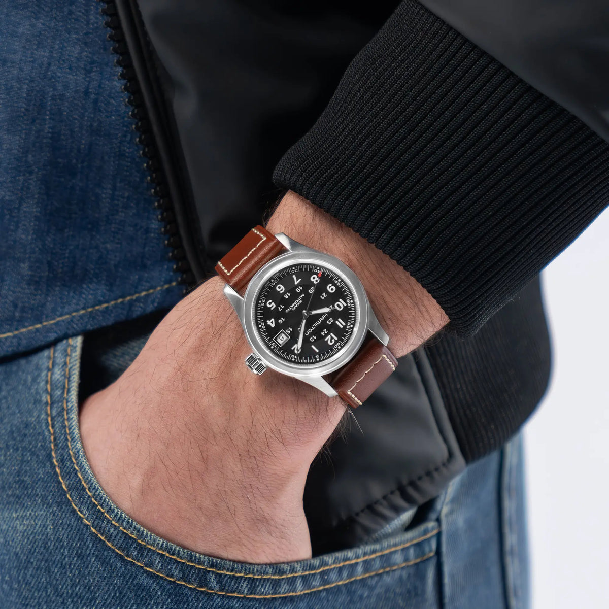 Wristshot mit der Hamilton Khaki Field Auto H70455533 mit schwarzem Zifferblatt an einem weiß abgenähtem braunen Lederband