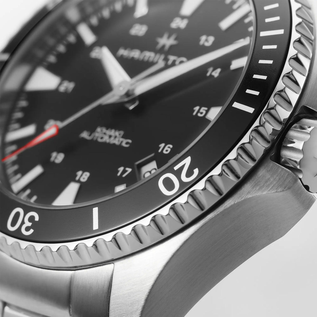 Detailaufnahme der Hamilton Taucheruhr Khaki Navy Scuba Auto H82335131 im 40mm-Edelstahlgehäuse mit schwarzem Zifferblatt und Lünette am Edelstahl-Armband zeigt die Struktur des Edelstahls und die Feinheiten der geriffelten Lünette