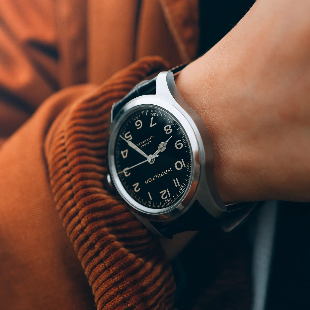 Mann trägt die Hamilton Murph H70405730 im 38mm-Edelstahl-Gehäuse und einem schwarzem Zifferblatt Indizes und Zeigern mit Vintage-Charakter an seinem Handgelenk