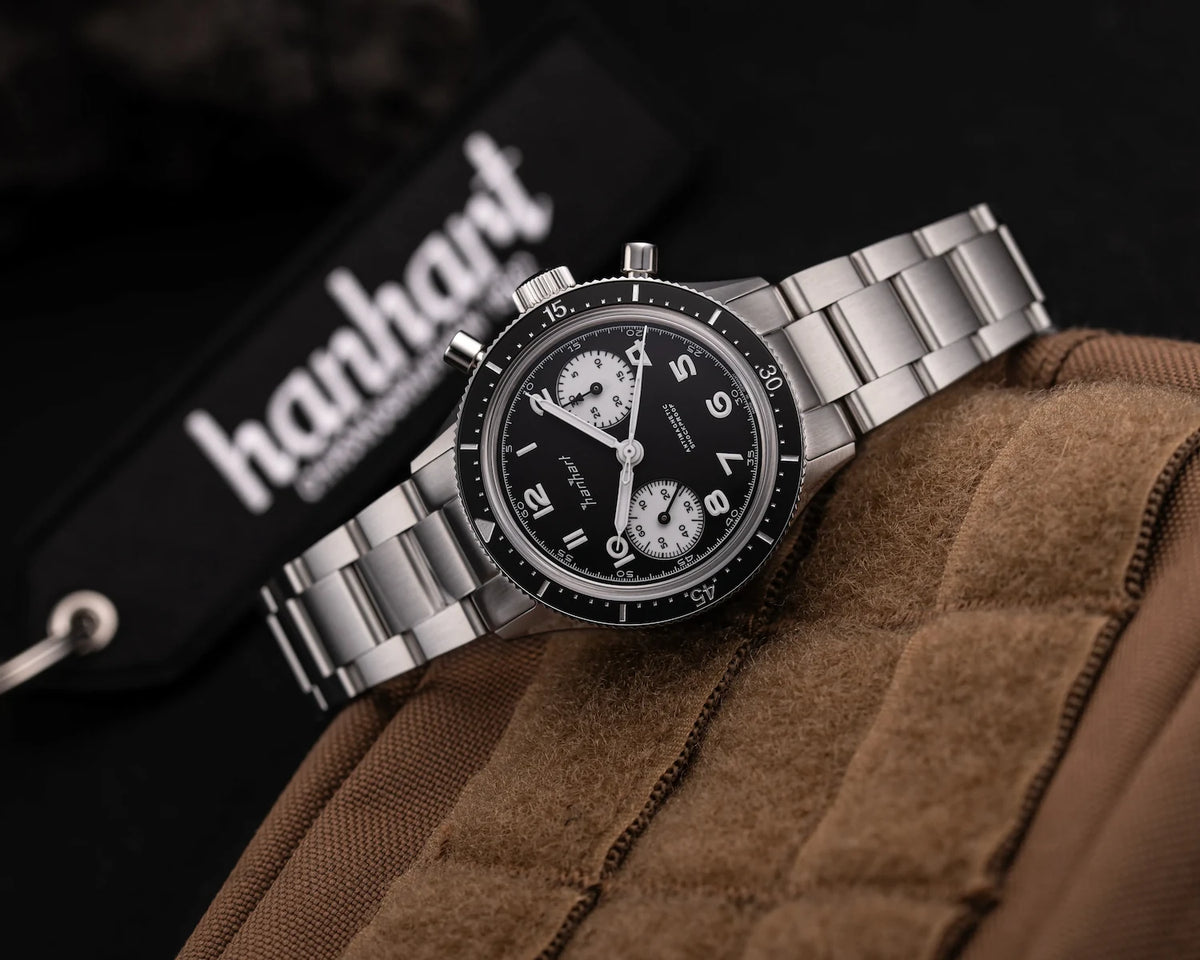 Produktfotografie des Hanhart 415 ES Chronographs mit dem Reverse-Panda-Zifferblatt in Schwarz mit weißen Sub-Dials am Edelstahlarmband