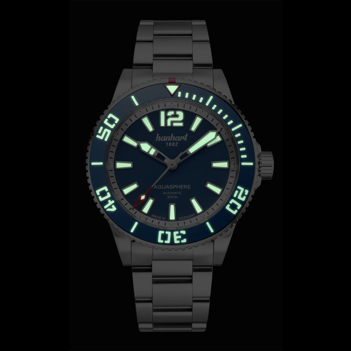 Frontale Ansicht der Hanhart Aquasphere mit dem blau-schwarz verlaufenden "Ocean Fade"-Zifferblatt und blauem  Keramik-Inlay auf der Lünette am Edelstahlarmband bei Nacht mit aktivierter Lreuchtmasse