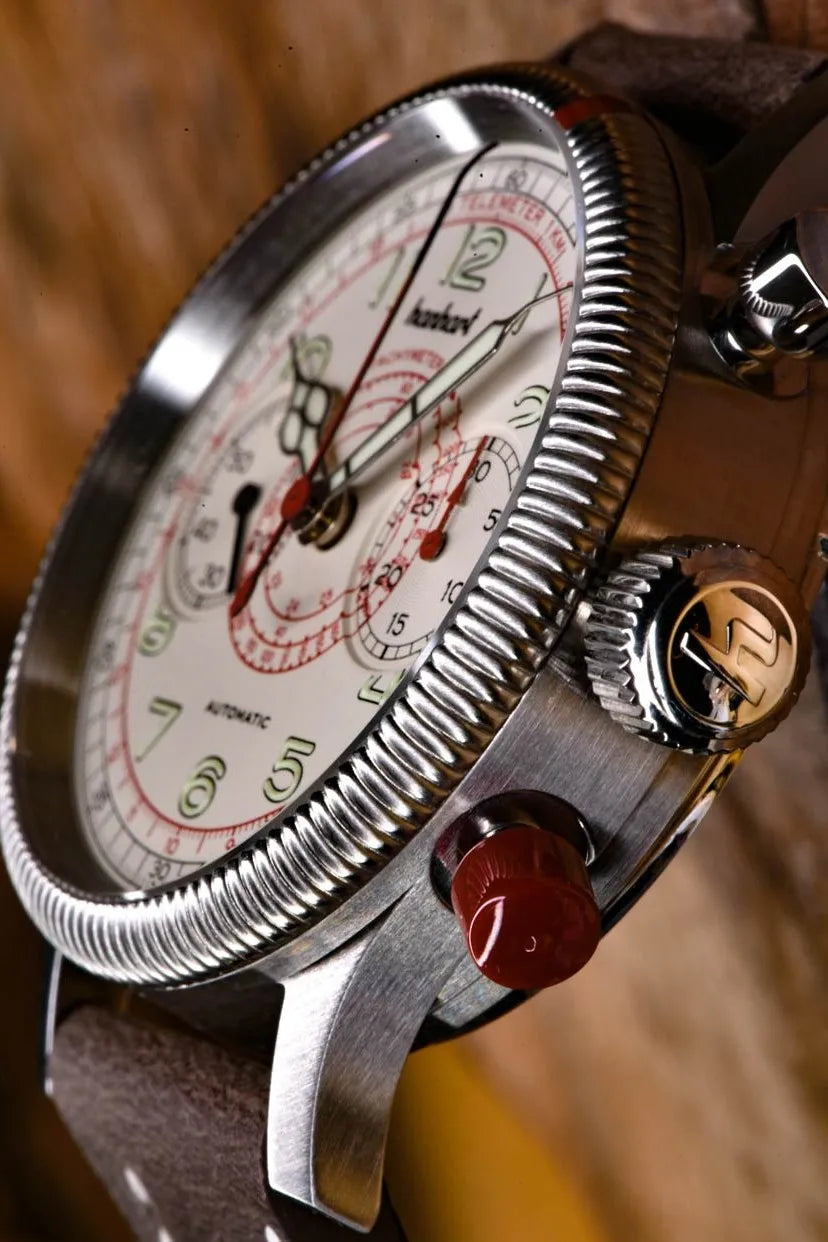 Seitliche Gehäuseflanke mit Pushern und Bandanstoß desHanhart Pioneer TachyTele Chronographs mit altweißem Zifferblatt und rot gehaltener Tachymeter-Skala und Telemeter-Skala am braunen Kalbslederband mit Niete