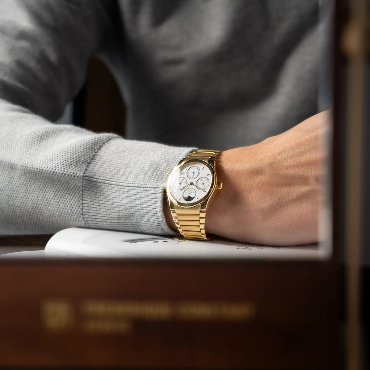 Mann mit grauem Pullover trägt die IWC Ingenieur Perpetual Calendar in Gelbgold mit weißem Zifferblatt und zughörigem Gelbgold-Armband an seinem Handgelenk