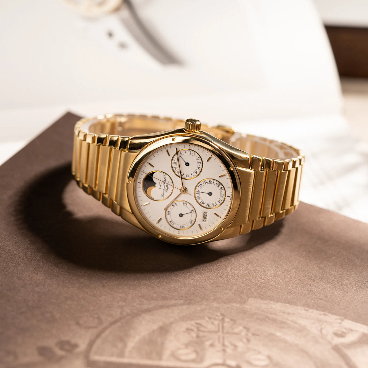 Produktfotografie der IWC Ingenieur Perpetual Calendar in Gelbgold mit weißem Zifferblatt und zughörigem Gelbgold-Armband