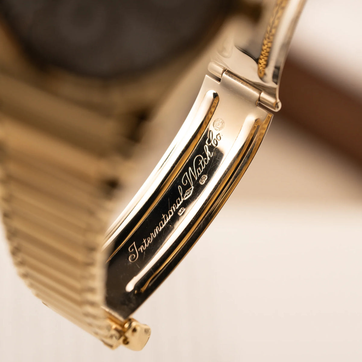 Detailaufnahme des "International Watch Co" Schriftzugs im Inneren der Faltschliesse der IWC Ingenieur Perpetual Calendar in Gelbgold mit weißem Zifferblatt und zughörigem Gelbgold-Armband