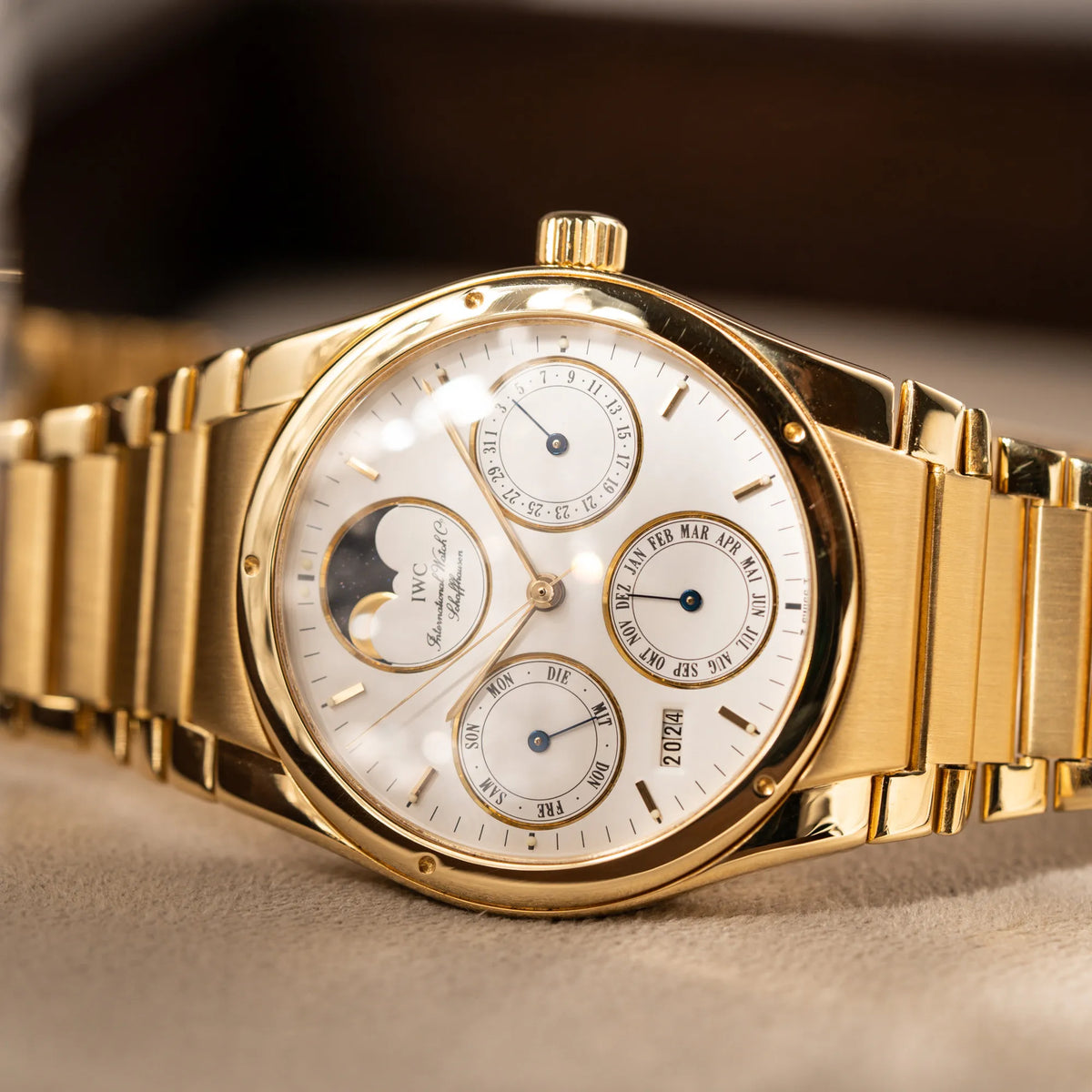 Seitlich liegende IWC Ingenieur Perpetual Calendar in Gelbgold mit weißem Zifferblatt und zughörigem Gelbgold-Armband