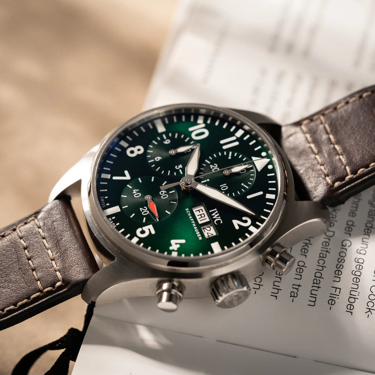 Produktfotografie des IWC Pilot 41 Chronographs IW388103 mit grünem Zifferblatt an einem braunen Lederband zeigt den Sonnenschliff des Zifferblatt im Licht